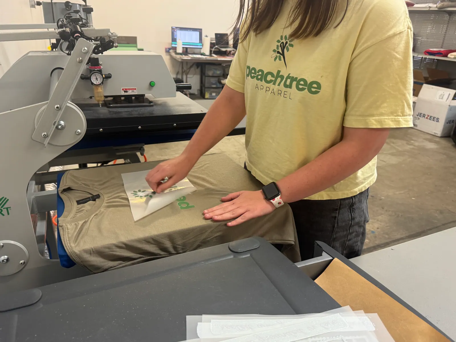 Positioning a DTF transfer film on an olive T-shirt at the heat press