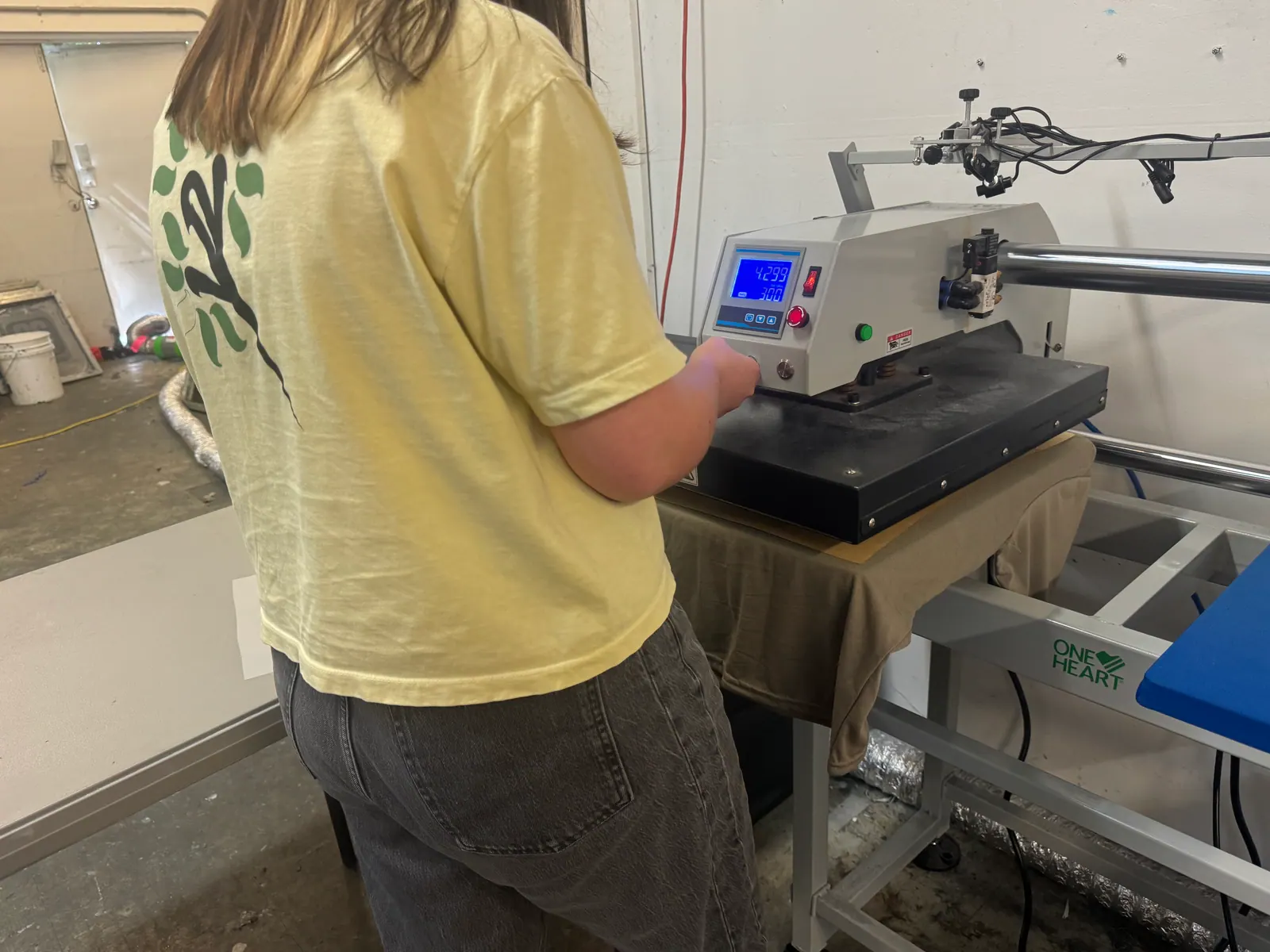 Team member running a digital heat press on the PeachTree Apparel shop floor